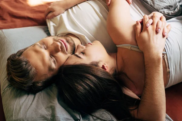 Overhead view of couple hugging and sleeping in bed — Stock Photo