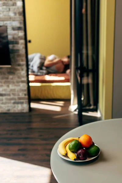 Selective focus of delicious fruits on table near couple in bedroom — Stock Photo