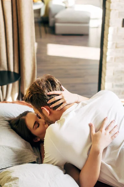 Woman with closed eyes kissing bearded boyfriend in bed — Stock Photo