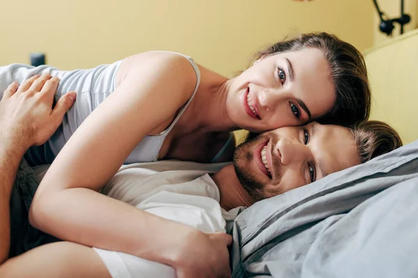 Усміхнена дівчина і хлопець обіймається в ліжку — стокове фото