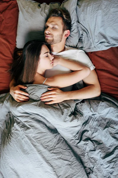 Vista superior de la novia y el novio abrazándose mientras duerme en la cama - foto de stock