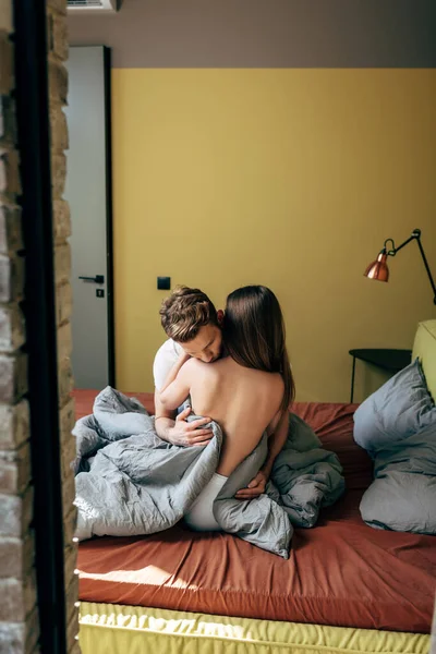 Messa a fuoco selettiva di uomo appassionato baciare spalla di fidanzata sensuale in camera da letto — Foto stock