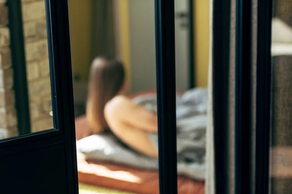 Selektiver Fokus der Tür in der Nähe einer sinnlichen Frau, die im Schlafzimmer liegt — Stockfoto