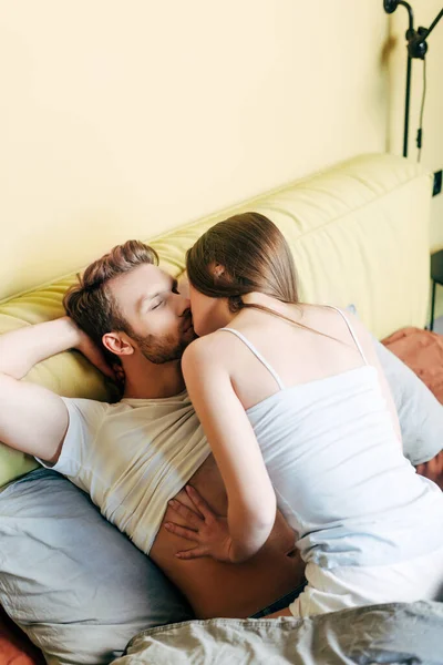 Mujer besos barbudo novio en dormitorio - foto de stock