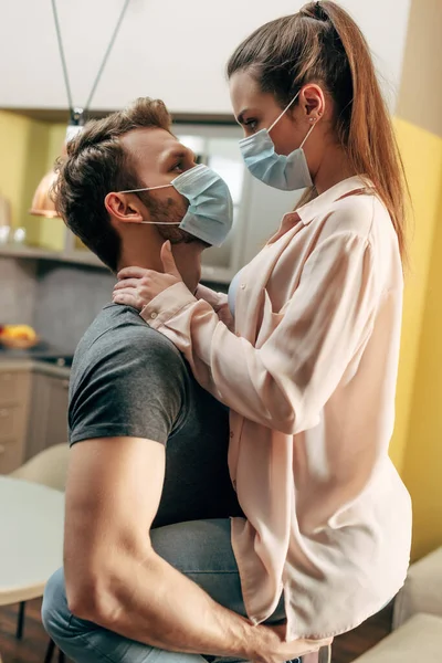 Homem em máscara médica segurando em braços menina na sala de estar — Fotografia de Stock