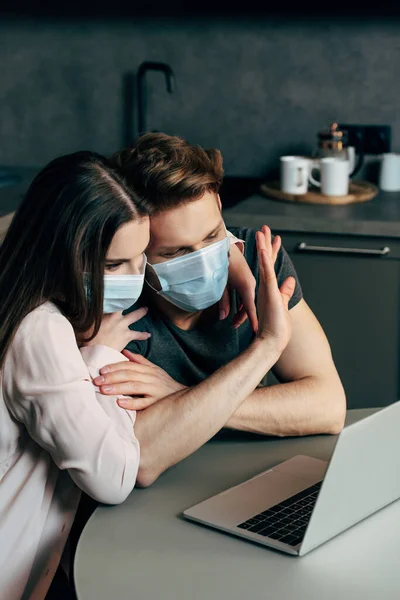 Selective focus of man in medical mask waving hand while having video chat near girlfriend — Stock Photo