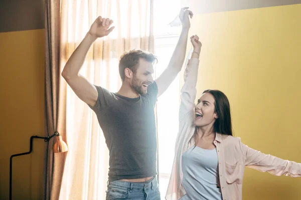 Pareja excitada sosteniendo máscaras médicas por encima de la cabeza, fin del concepto de cuarentena - foto de stock