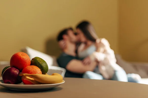 Selective focus of tasty fruits near sexy couple kissing in living room — Stock Photo