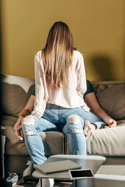 Vista trasera de la chica sensual sentado en el hombre en la sala de estar — Stock Photo