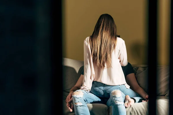 Visão traseira da mulher sensual sentado no homem na sala de estar — Fotografia de Stock