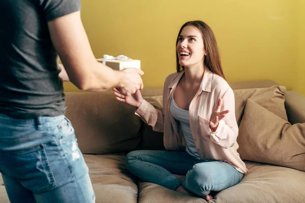 Selective focus of happy woman looking at boyfriend with gift box — Stock Photo