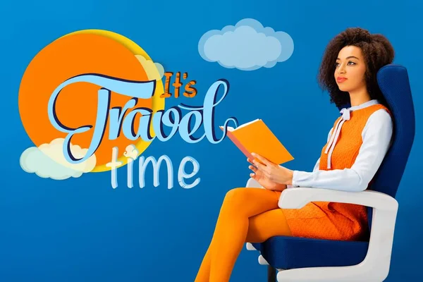 Mulher americana africana em vestido laranja retro sentado no assento e segurando livro em azul com ele é ilustração do tempo de viagem — Fotografia de Stock