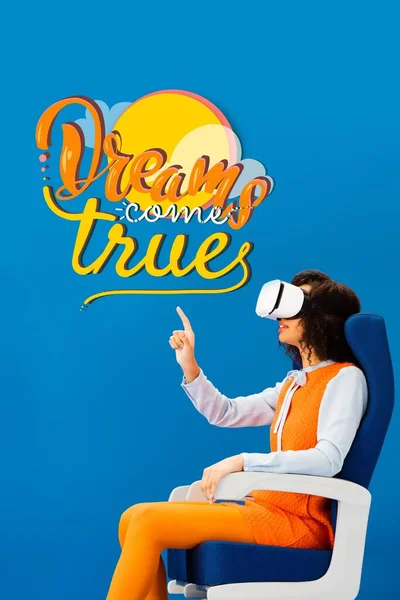 Side view of african american with vr headset pointing with finger at dreams come true illustration on blue background — Stock Photo