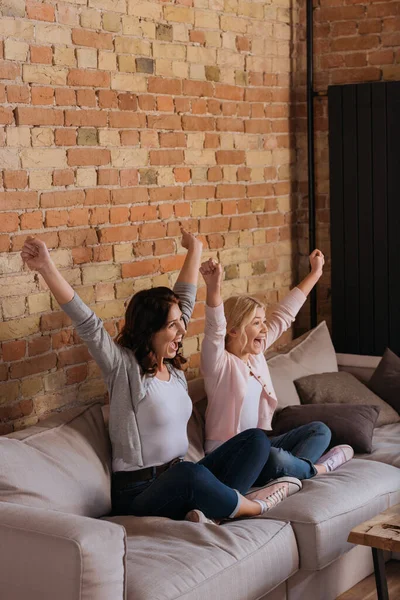 Happy mother and daughter sitting on couch at home — Stock Photo