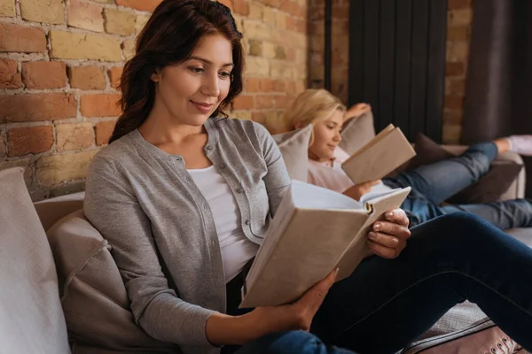 Selektiver Fokus der Frau, die Buch in der Nähe ihrer Tochter auf dem Sofa liest — Stockfoto