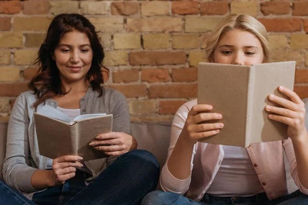 Enfoque selectivo de la mujer sonriente con niños leyendo libros en el sofá - foto de stock
