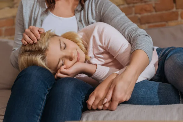 Child with closed eyes lying on couch near mother — Stock Photo