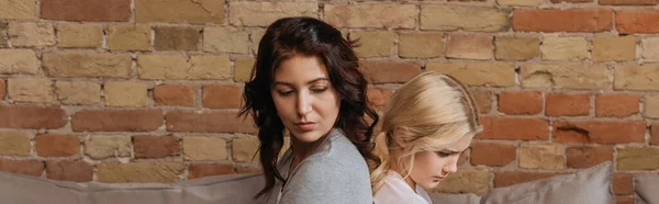 Side view of sad child sitting back to back with mother on couch, panoramic crop — Stock Photo