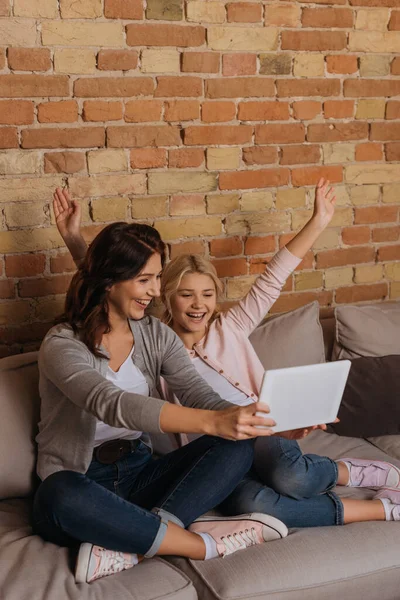 Criança feliz e mãe olhando para tablet digital no sofá — Fotografia de Stock