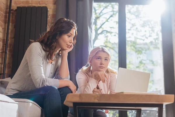 Selektiver Fokus der Mutter, die während der Online-Bildung zu Hause neben dem nachdenklichen Kind sitzt — Stockfoto