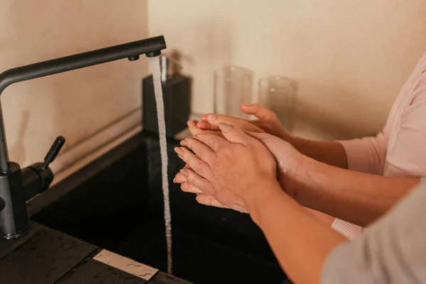 Vista recortada de la madre y el niño lavándose las manos en la cocina - foto de stock