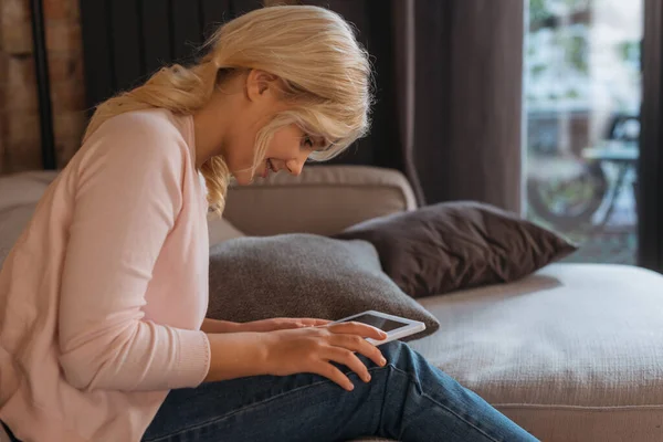 Seitenansicht eines lächelnden Kindes mit digitalem Tablet im Wohnzimmer — Stockfoto