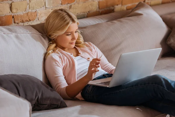 Selective focus of cute child using laptop on couch at home — Stock Photo