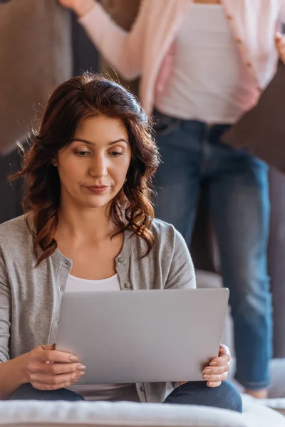 Selective focus of woman using laptop near daughter on couch — Stock Photo