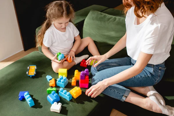 Lockige Mutter und süße Tochter spielen Bauklötze im Wohnzimmer — Stockfoto