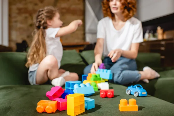 Selective focus of redhead mother and cute daughter playing building blocks in living room — Stock Photo