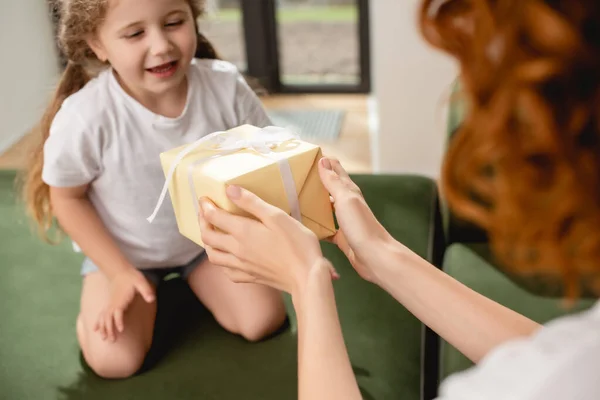 Selective focus of curly mother giving present to cute daughter — Stock Photo