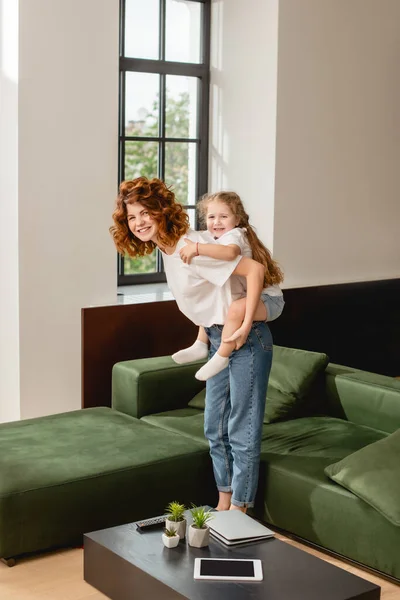 Curly mother piggybacking happy daughter — Stock Photo