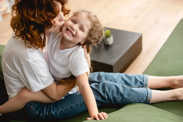 Encaracolado mãe beijos bochecha de feliz filha — Fotografia de Stock