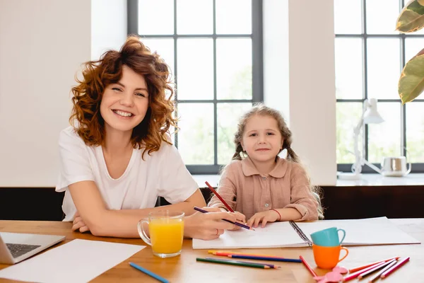 Madre riccia che disegna con figlia felice a casa — Stock Photo