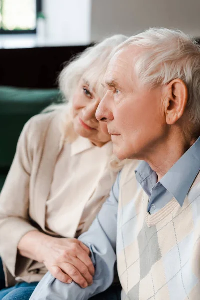 Chateado casal sênior abraçando e sentado em casa em quarentena — Fotografia de Stock