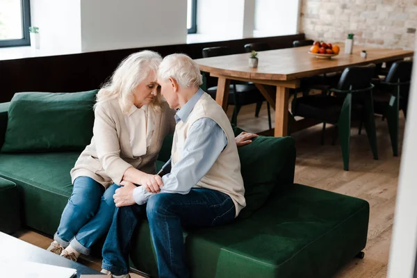 Sad elderly wife and husband hugging and sitting at home on quarantine — Stock Photo