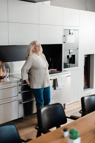 Anciana triste y solitaria parada en la cocina durante la cuarentena — Stock Photo