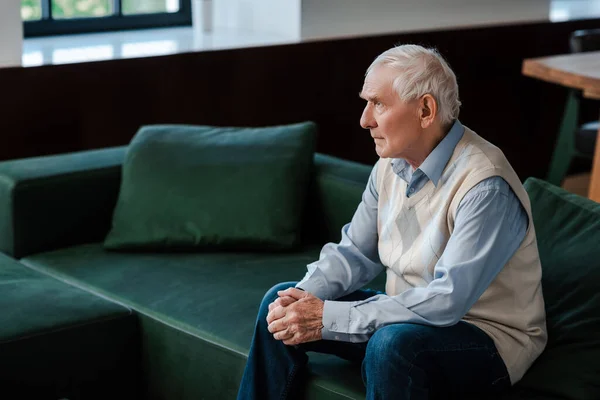 Sad lonely elderly man sitting on sofa during self isolation — Stock Photo