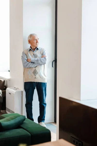 Älterer Mann während Quarantäne mit verschränkten Armen am Fenster — Stockfoto
