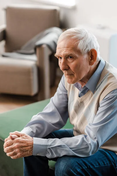 Anciano solitario sentado en el sofá durante la cuarentena - foto de stock