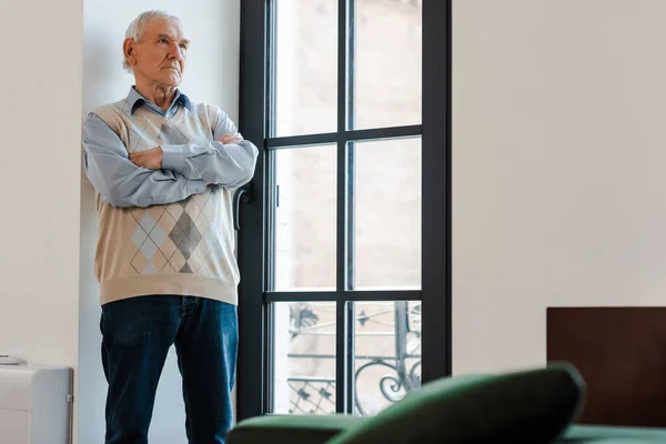 Trauriger einsamer Mann mit verschränkten Armen am Fenster während der Quarantäne — Stockfoto