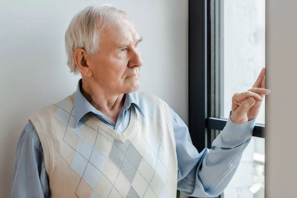 Lonely man looking through window during self isolation — Stock Photo