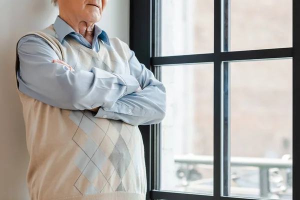 Ausgeschnittene Ansicht eines einsamen Mannes mit verschränkten Armen, der während der Quarantäne am Fenster steht — Stockfoto