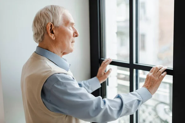 Triste homem idoso olhando através da janela durante a quarentena — Fotografia de Stock