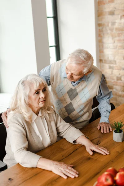 Sad elderly couple sitting at home together on self isolation — Stock Photo