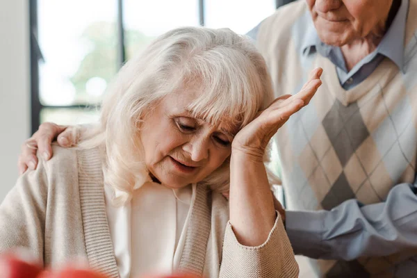 Ältere Frau mit Kopfschmerzen zu Hause bei Ehemann während der Selbstisolierung — Stockfoto