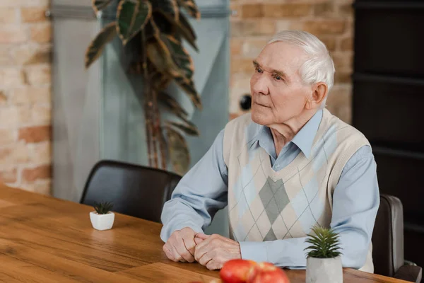Одинокий пожилой человек с фруктами и растениями на столе во время самоизоляции — стоковое фото