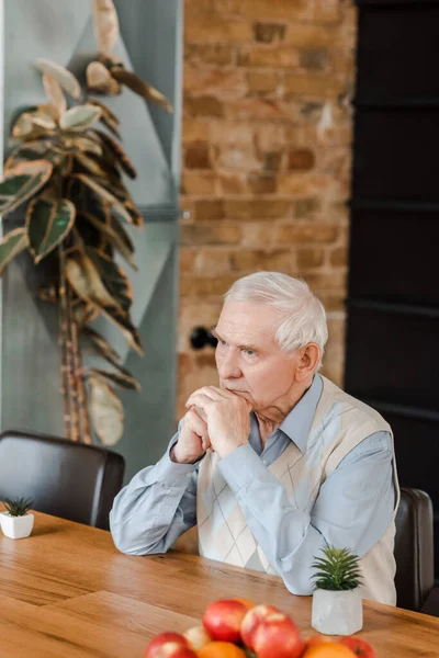 Заботливый пожилой человек с фруктами и растениями на столе во время самоизоляции — стоковое фото