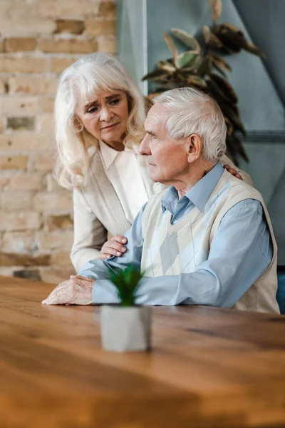 Sconvolto moglie anziana e marito abbracciare e seduto a casa in quarantena — Foto stock