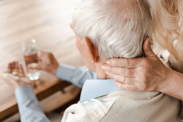 Couple âgé malade avec des pilules et un verre d'eau à la maison sur l'isolement personnel, foyer sélectif — Photo de stock